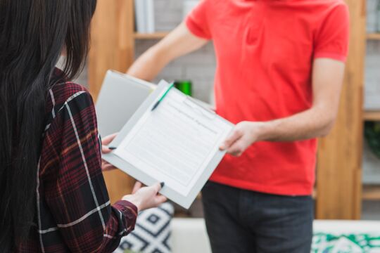 crop-courier-giving-clipboard-customer